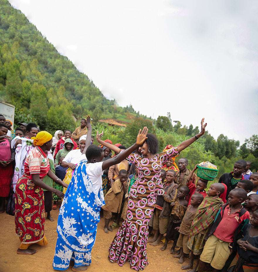 Coffee distributor Jeanine Niyonzima-Aroian dances with a colorful crowd of onlookers in Burundi, East Africa