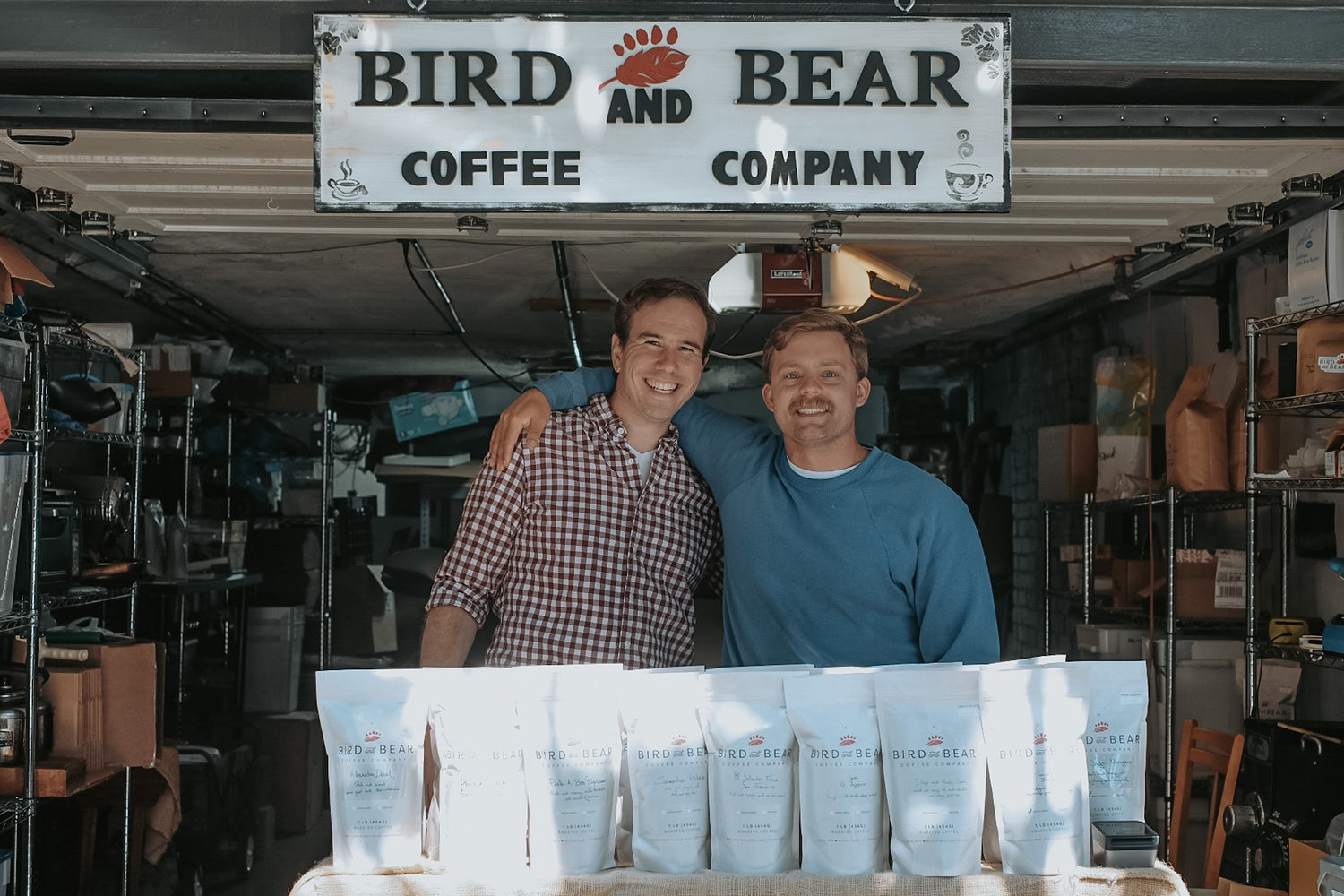 Dan and Carson smile with arms over each others shoulders, inside Bird and Bear Coffee pop-up at 726 Cole St.